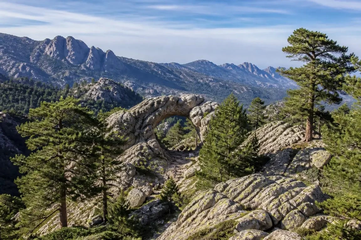 Trou de la bombe corse randonnée : arche naturelle du massif de Bavella avec pins laricio et relief montagneux