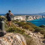 Guide randonnée corse du sud : chaussures et gourde sur un rocher, sentier littoral et mer turquoise